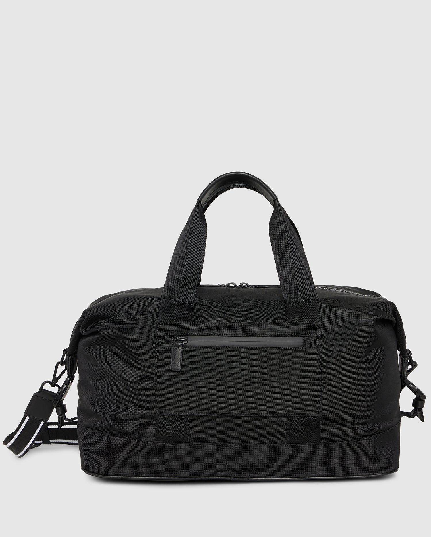 A sleek black MENS WEEKENDER BAG - B6A629Z1BG by Psycho Bunny with a front zippered pocket, two sturdy handles, and an adjustable shoulder strap. The bag has a minimalist design, with clean lines and a smooth finish, suitable for travel or gym use.