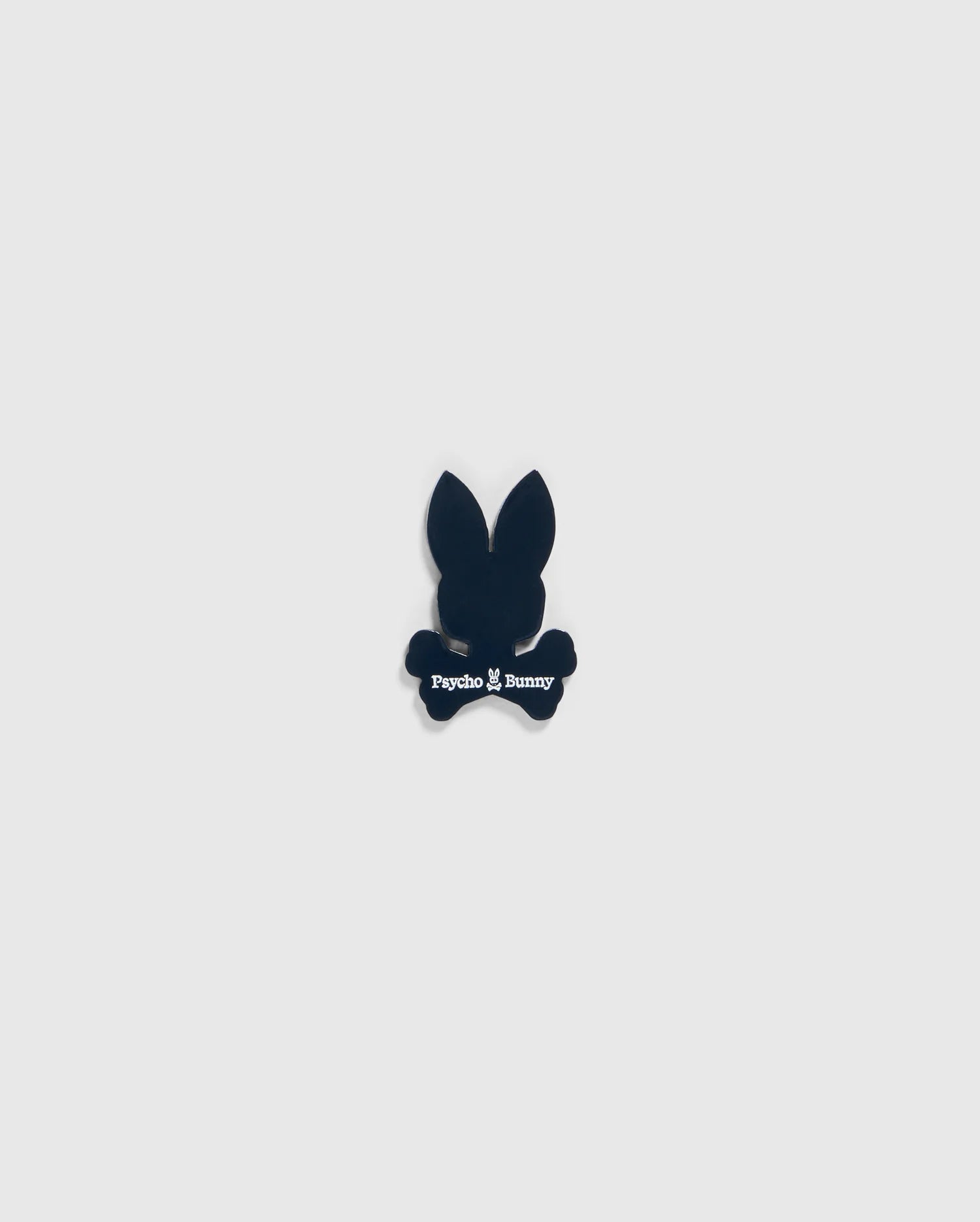 A small black silhouette of a bunny head with long ears and crossbones underneath, featuring the text "Psycho Bunny" in white below the head and above the crossbones, designed as an edgy BALL MARKER - B6A698C200 perfect for any golfer's collection by Psycho Bunny.