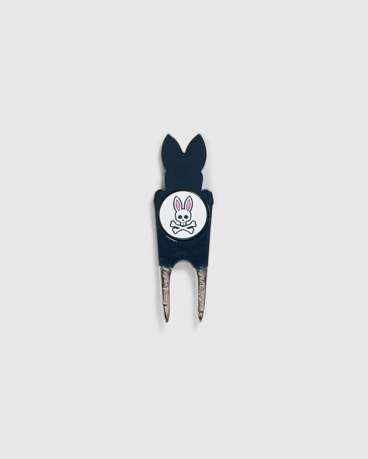 A Psycho Bunny DIVOT TOOL - B6A699C200 featuring a black handle with a white circular logo. The logo shows an illustration of a bunny head with crossed bones underneath. The two prongs of the tool are metal, and it includes a magnetic ball marker. Ideal for those seeking unique golf gifts.