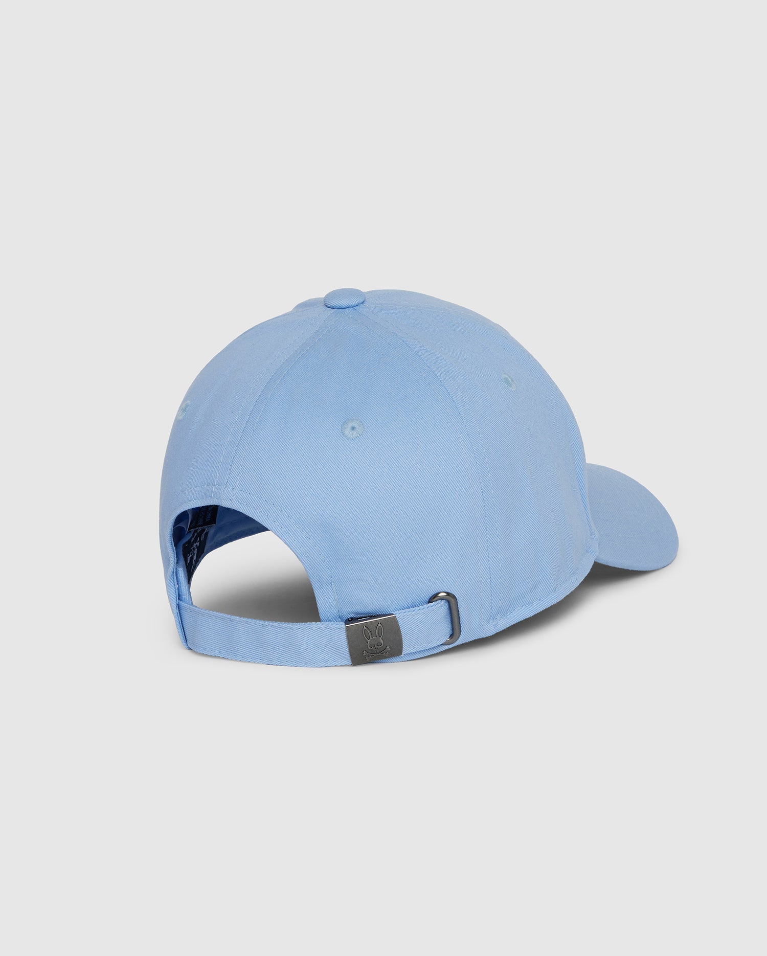 The Psycho Bunny MENS CLASSIC BASEBALL CAP - B6A816B200 is displayed from the back, showcasing its classic light blue color and crafted from 100% cotton. It features an adjustable strap with a metal clasp and is set against a plain white background.