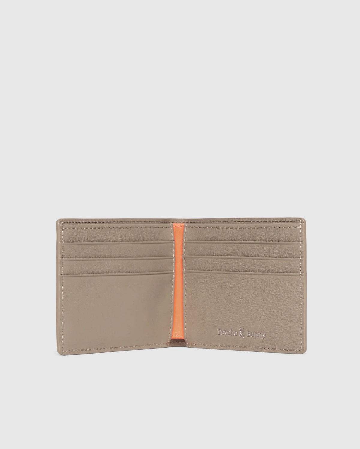 A luxury Psycho Bunny men's leather wallet is open, showcasing multiple card slots and an orange interior accent. The brand name is embossed in silver on the bottom right corner. The plain light gray background highlights the elegance of this premium accessory.