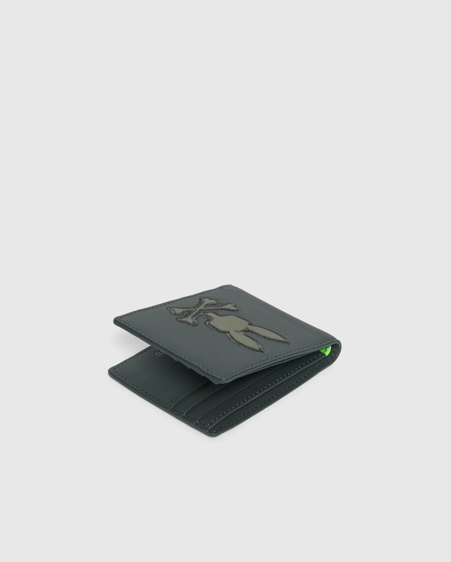 A fashionable leather wallet in green from Psycho Bunny, boasting a stitched rabbit design on the front. The MENS WORDMARK LEATHER WALLET - B6A868D200 is tailored for men with a folded design that reveals visible card slots, set against a simple, light background.