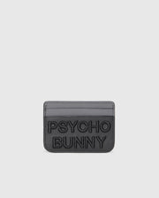 The MENS LEATHER CARD CASE - B6A869D200 by Psycho Bunny is a gray leather card holder with embossed "PSYCHO BUNNY" text on the front and two card slots against a sleek white backdrop. Crafted from premium leather, it offers a minimalist design.