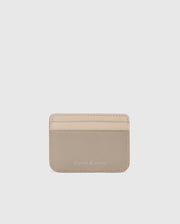 The MENS LEATHER CARD CASE - B6A869D200 by Psycho Bunny is a compact light beige leather card holder with two slots and an elegant "Psycho Bunny" embossing on the lower front. Photographed against a white background, it highlights the sleek design.
