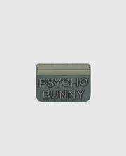The MENS WORDMARK LEATHER CARD CASE - B6A869D200 by Psycho Bunny is a green, minimalist leather card holder made from durable shell pebble leather. It features two card slots, "PSYCHO BUNNY" embossed on the front with raised text, and a soft matte finish.