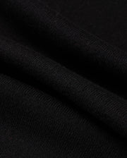 Close-up of the MENS MONROE TWILL PATCH SCARF by Psycho Bunny, highlighting its black wool blend material with intricate texture and weaving pattern featuring multiple folds. The soft, subtly ribbed fabric suggests an air of elegance and luxury textile craftsmanship.