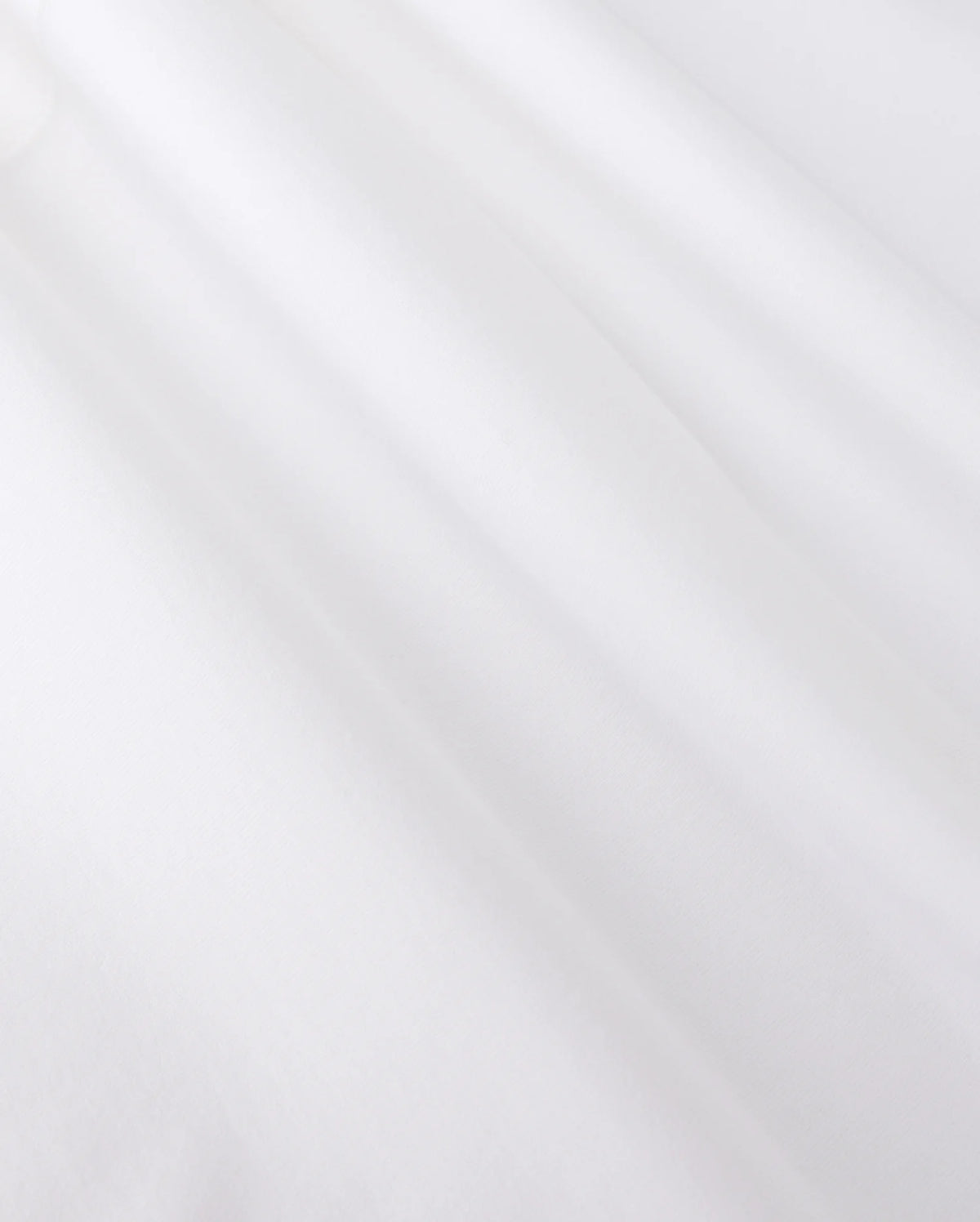 Close-up of smooth, white jersey fabric with gentle shadows forming soft folds. The texture appears soft and slightly matte, reminiscent of the MENS ARTHUR JERSEY SHIRT - B6C748D200 by Psycho Bunny, evoking a sense of lightness and simplicity.