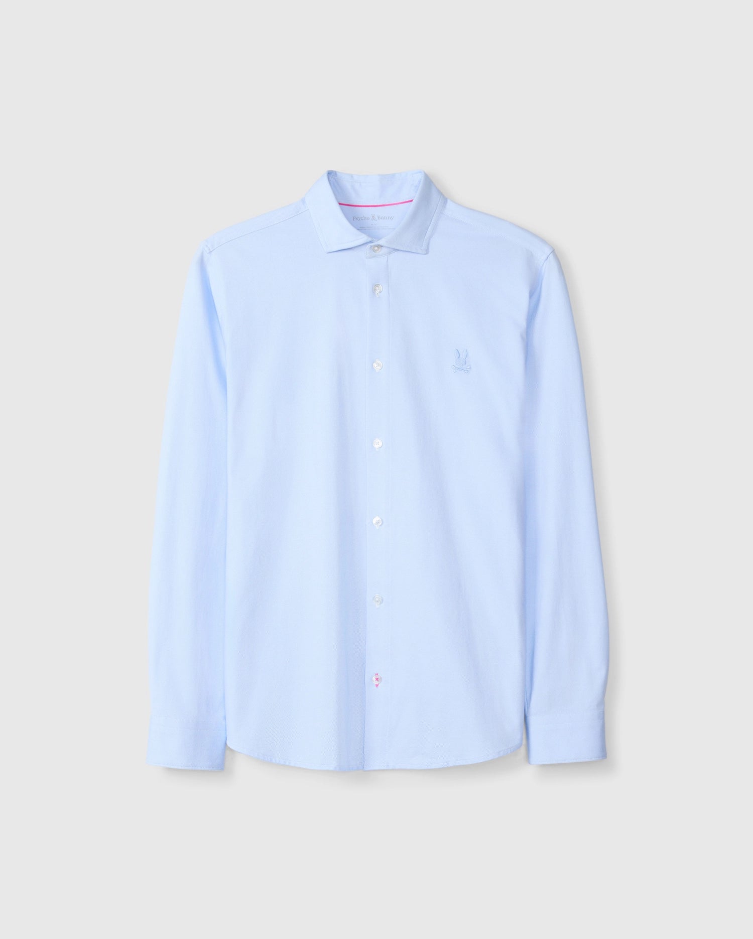 The Psycho Bunny MENS BRENDAN JERSEY SHIRT - B6C749D200 is a light blue button-up shirt with long sleeves and a crisp collar, featuring an embroidered chest Bunny logo. Made from soft Pima cotton, the shirt is neatly pressed and displayed against a plain background.