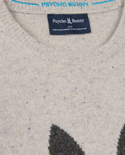 Close-up of the gray MENS LINCOLN MERINO WOOL SWEATER - B6E831D200 by Psycho Bunny, showcasing a black and white logo of a bunny with crossed bones. The collar tag displays "Psycho Bunny" along with the size information and merino wool details beneath. The speckled texture enhances the sweater's timeless appeal.