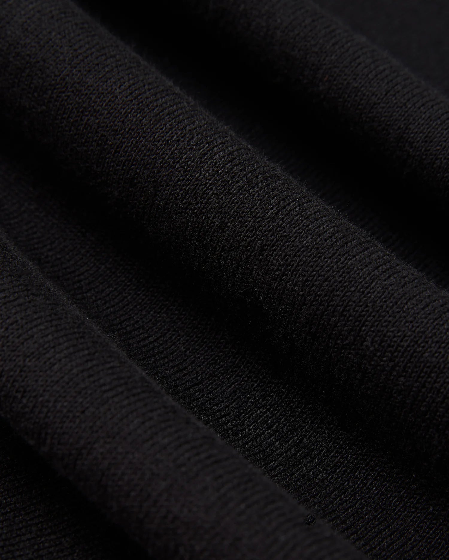 A detailed view of the Psycho Bunny MENS BELMORE EXTRA FINE COTTON SWEATER - B6E832D200 showcases the intricate ribbed texture formed by parallel lines in its extrafine cotton knit. The lighting accentuates the sweater's high-quality stitching, enhancing its soft and luxurious look.