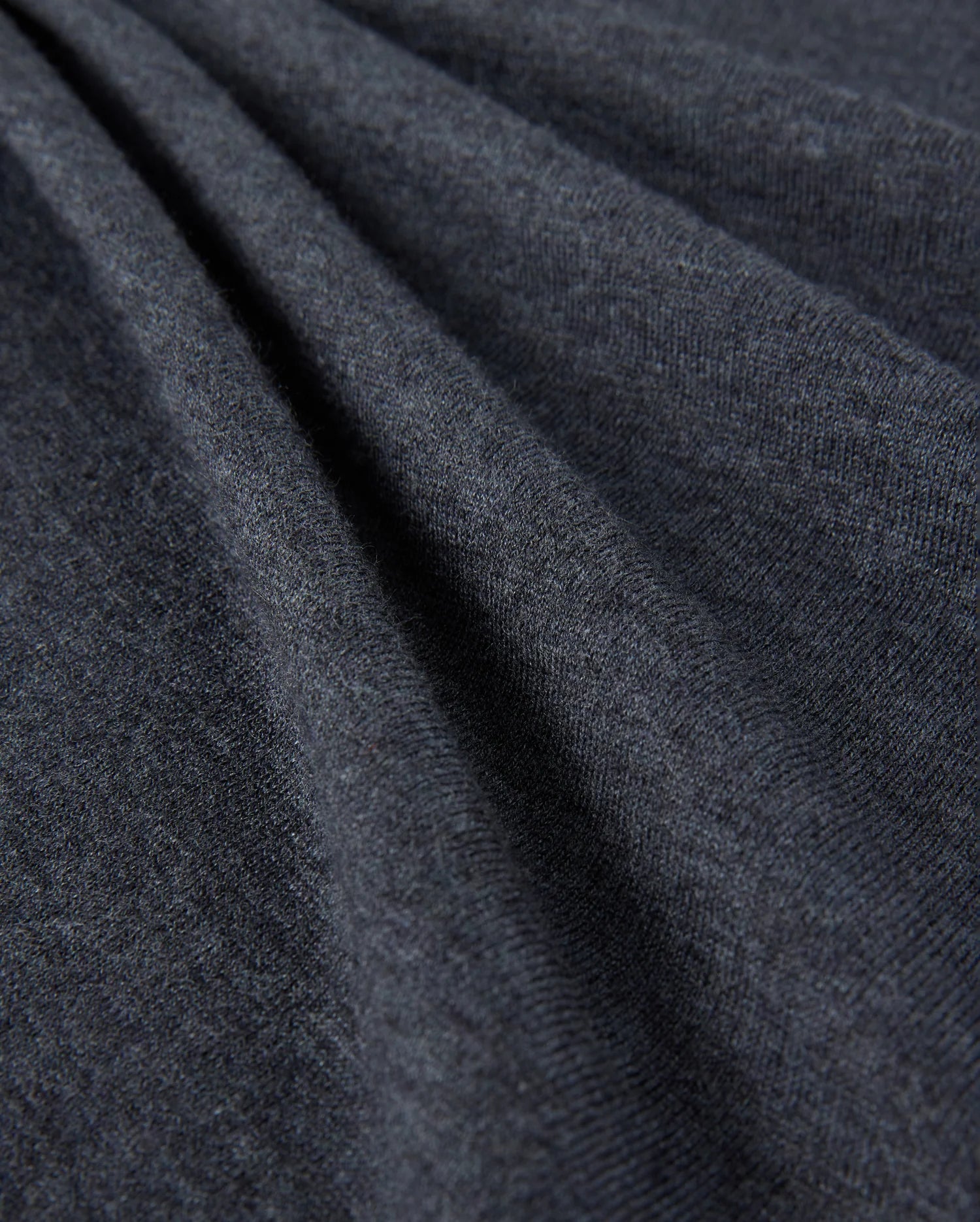 Close-up of the Psycho Bunny Men's Bradshaw Polo Sweater - B6E835D200, showcasing its dark gray fabric with a soft, smooth texture and gentle folds. The surface appears slightly fuzzy, indicating that this premium merino wool material is warm and comfortable, perfect for a luxury polo sweater.