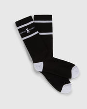 A pair of black knee-high Psycho Bunny fashion socks with white toe and heel patches and two white horizontal stripes near the top, featuring the text "PSYCHO BUNNY" in white.