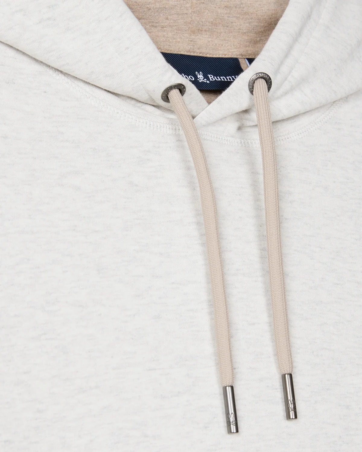 Close-up of the Psycho Bunny MENS JAMES PREMIUM HOODIE - B6H789D200 in light gray, featuring beige drawstrings with metallic tips. A small part of the clothing tag is visible at the neckline. The soft, textured fabric ensures stylish warmth.