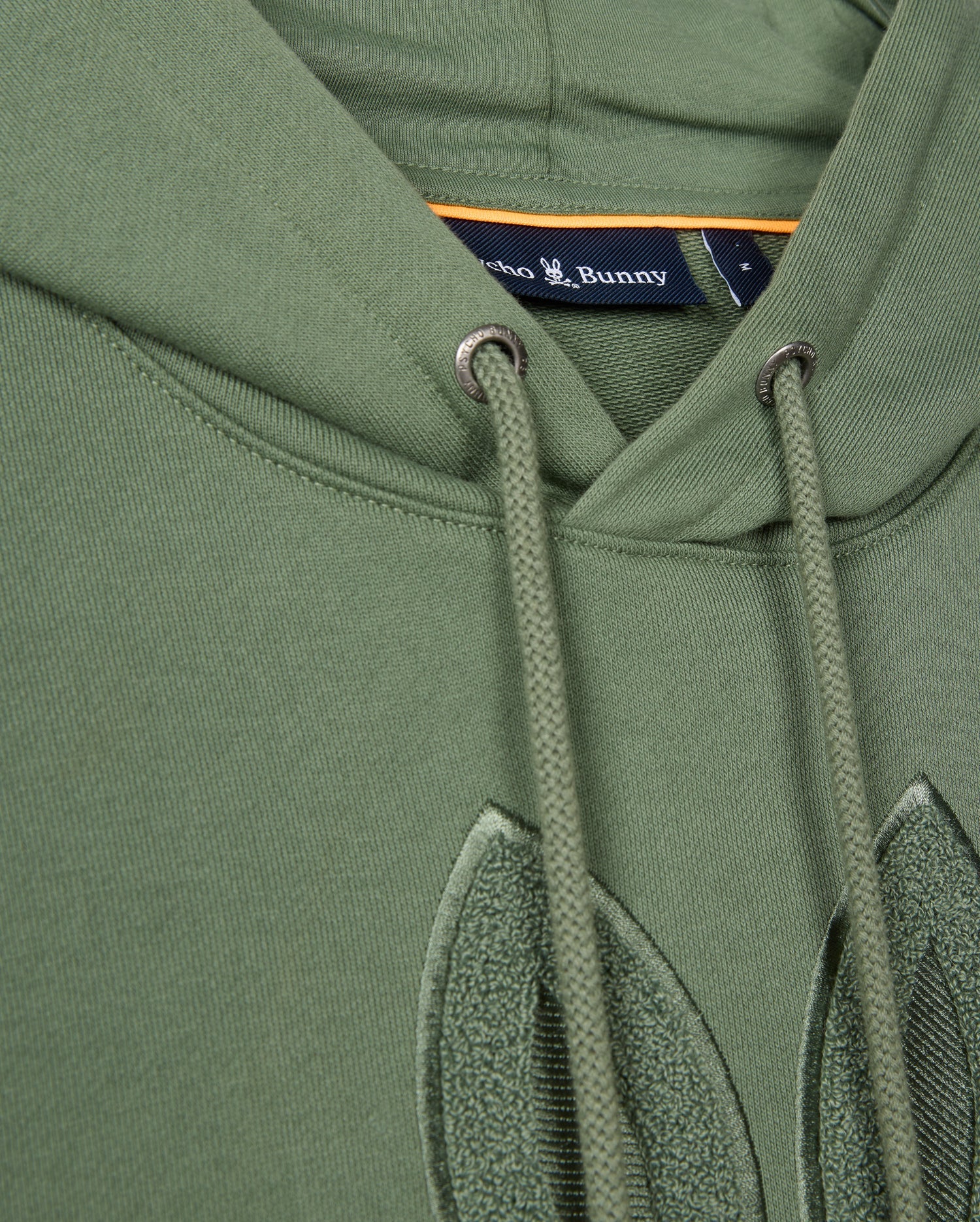 Close-up of the Psycho Bunny MENS PACIFIC CHENILLE HOODIE - B6H930D200 in green with drawstrings, showcasing a label and stitched detailing. Crafted from soft French terry, it features exquisite chenille embroidery for added texture.