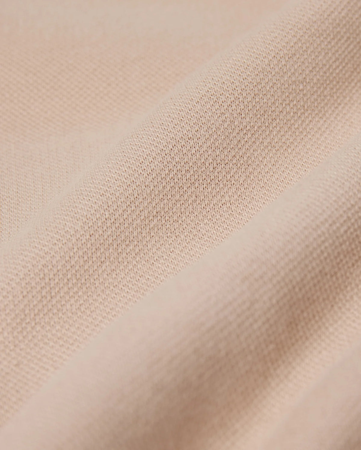 Close-up of a beige fabric featuring a textured, woven surface. The material resembles the fine weave found in the Psycho Bunny MENS BEDFORD SHIRT JACKET - B6J290B200, appearing soft and slightly crumpled, highlighting its smooth texture.