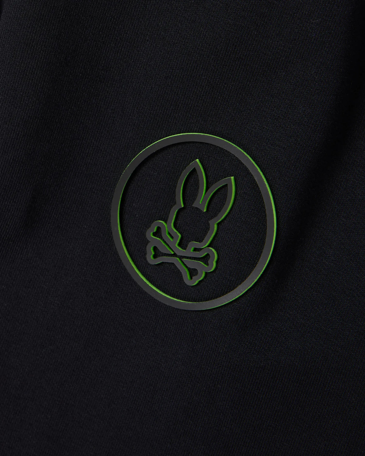 The edgy and modern design of a black background with a green outlined circle featuring a silhouette of bunny ears and crossbones pairs perfectly with the versatile style of the Psycho Bunny MENS MYKEL MIXED MEDIA JACKET - B6J875D200.