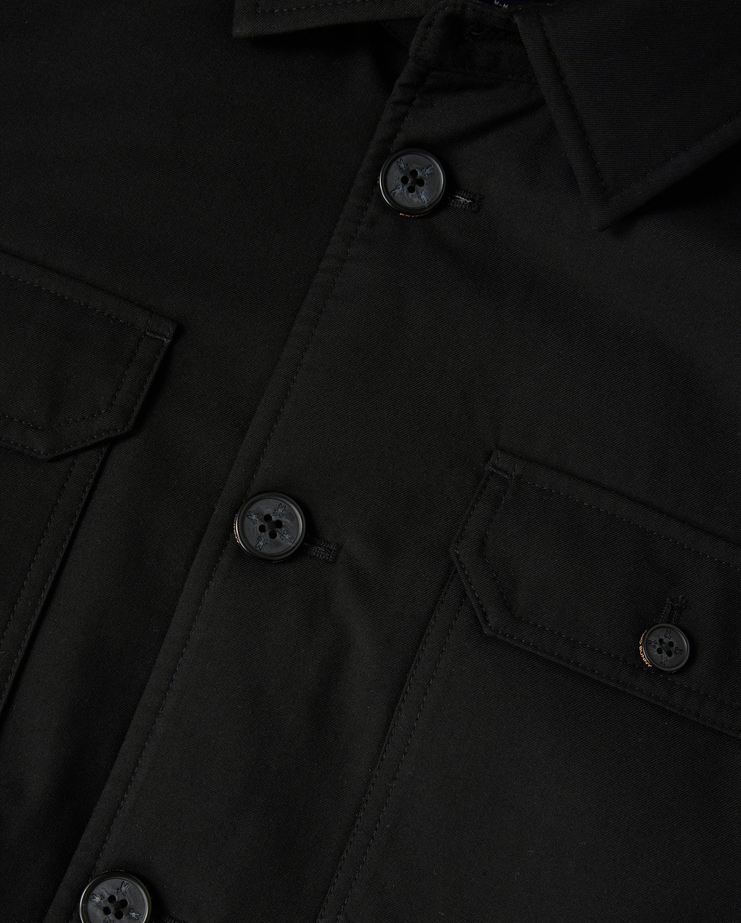 The Psycho Bunny Men's Hillcrest Padded Shacket (B6J936D200) features a black fabric with a collar, buttoned front, and two chest flap pockets with buttons. The neon lining adds vibrancy, while the textured fabric and detailed stitching are prominently showcased.