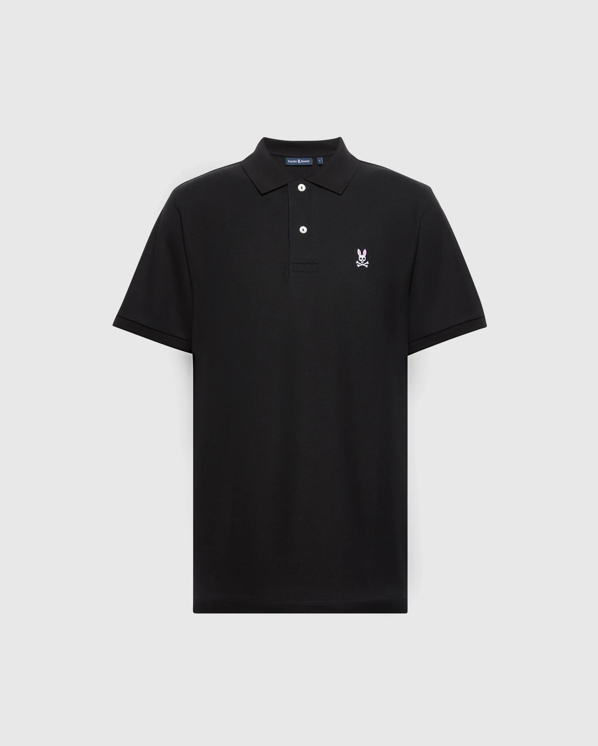 A Psycho Bunny men's black piqué polo shirt featuring a collar with two buttons and a white rabbit emblem with crossed ears and skull on the left chest. The diamond-knit fabric provides classic style, set against a light gray background. Model: MENS CLASSIC PIQUE POLO SHIRT - B6K001ARPC.