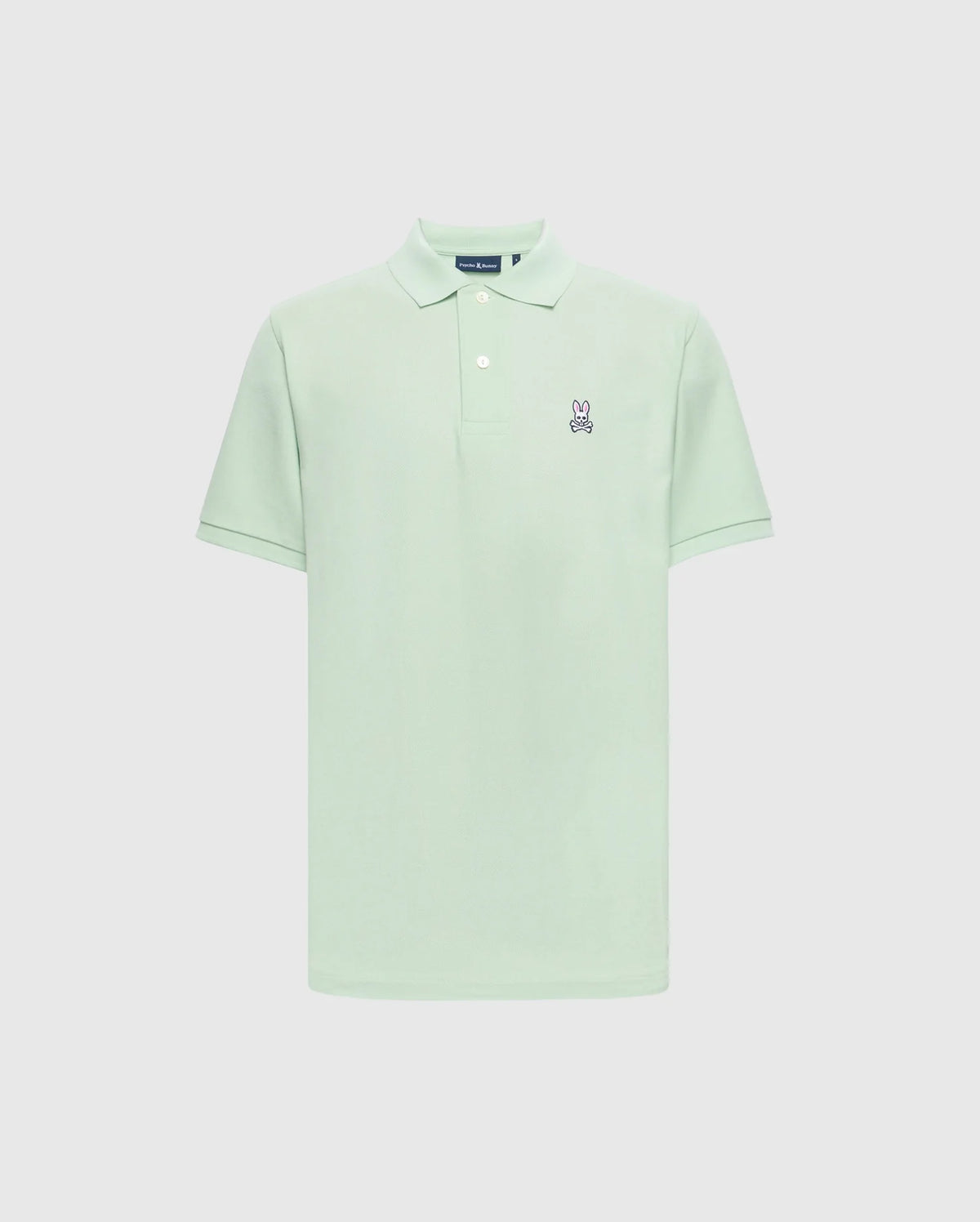 The Psycho Bunny MENS CLASSIC PIQUE POLO - B6K001F200 in light green is crafted from soft Pima cotton, featuring a classic collar, short sleeves, and two white buttons on the placket. It has a small embroidered bunny logo with crossed bones on the left chest against a plain white background.