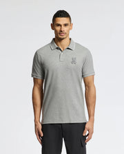 A man in a Psycho Bunny MENS ELDORADO PIQUE POLO (gray Peruvian Pima cotton, with a chenille bunny logo) and black pants poses against a plain white background.