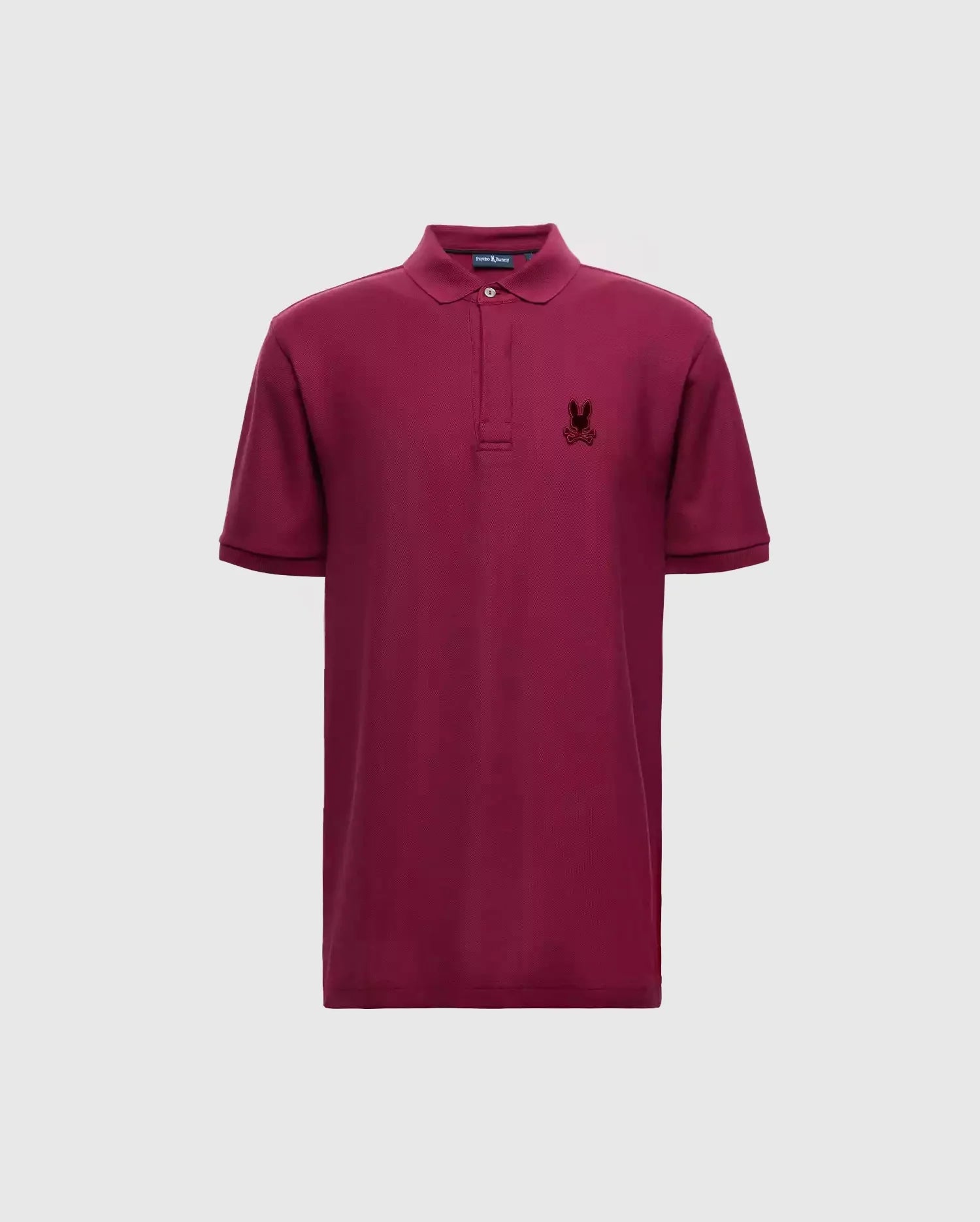 Introducing the Psycho Bunny Men's Branson Pique Polo - B6K108E200: a luxurious maroon polo shirt crafted from Pima cotton, complete with short sleeves and a collar. It features a small embroidered logo on the left chest, providing an elegant contrast against the plain light gray backdrop.