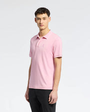 A person in a Psycho Bunny light pink MENS BRYCE PERFORMANCE PIQUE POLO with an embroidered chest logo stands against a white background. They have short dark hair, look slightly left, and wear dark pants.
