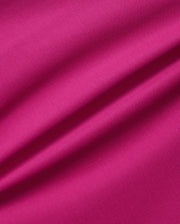 A close-up image of a vibrant pink, breathable Pima cotton fabric showcasing its texture. The material appears slightly wrinkled, with noticeable ripples running diagonally across the image, emphasizing the solid pattern's detail and quality in this Psycho Bunny Men's Richards Johnny Collar Pique Polo Shirt - B6K641C200.
