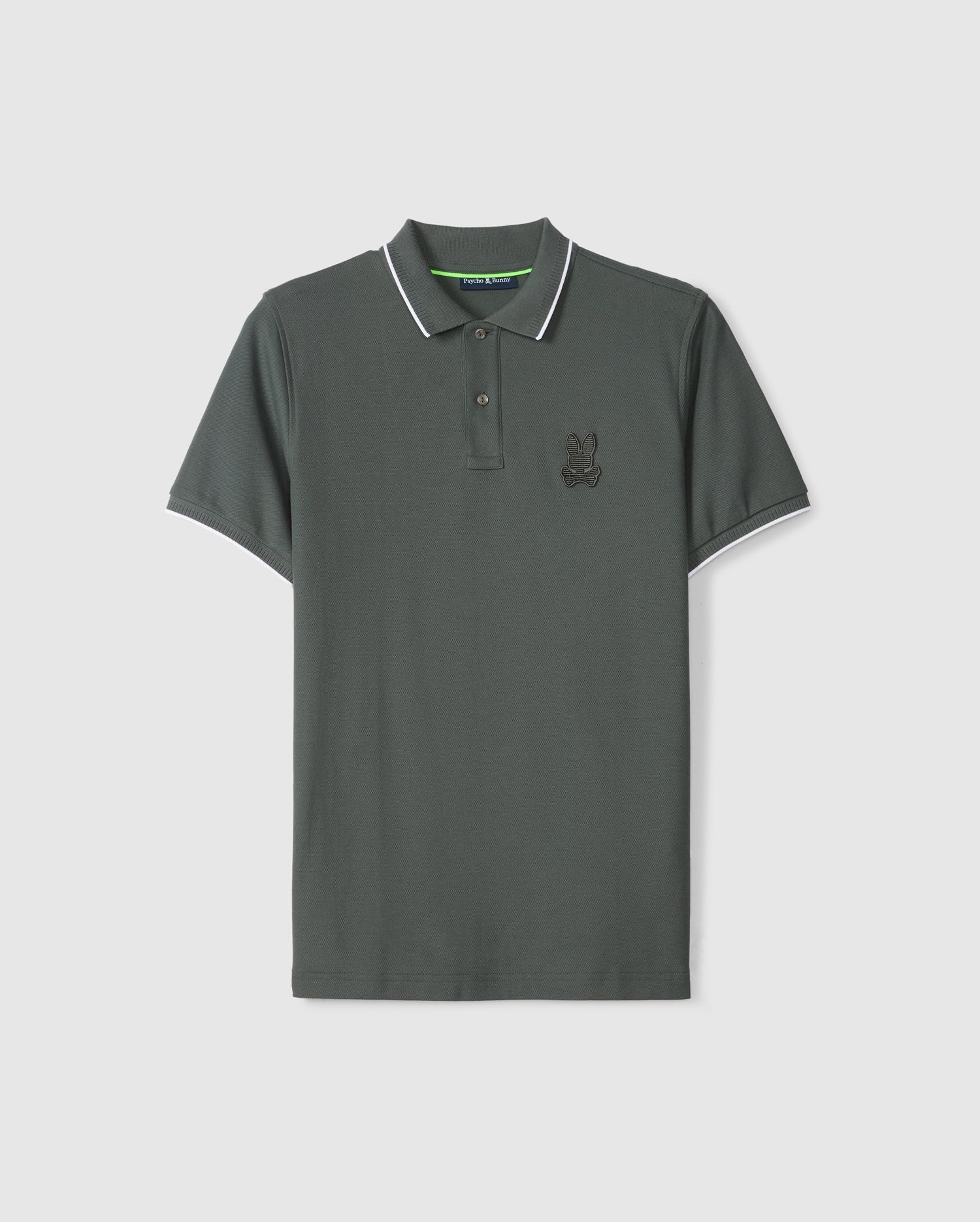 The Psycho Bunny MENS KINGSTON PIQUE POLO SHIRT - B6K764D200 is a dark green polo shirt made from luxurious Pima cotton. It features a collar and short sleeves with white trim along the edges, and an embroidered Bunny patch on the left chest. The shirt is displayed against a plain white background.