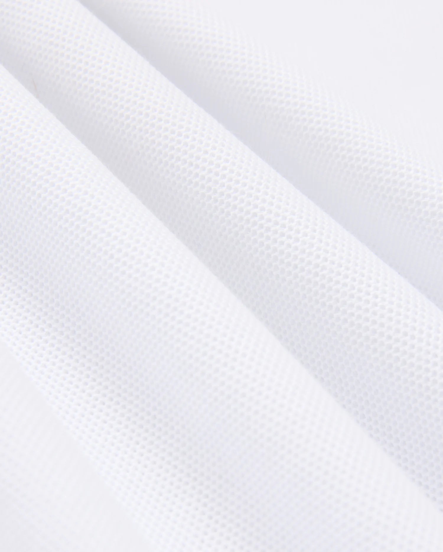 Close-up of a white, textured MENS KINGSTON PIQUE POLO SHIRT - B6K764D200 by Psycho Bunny, made from soft Pima cotton with a subtle waffle pattern. The fabric is shown in folds, highlighting its texture and softness. The image captures the intricacies of the material, emphasizing the small, raised squares that create the waffle effect.