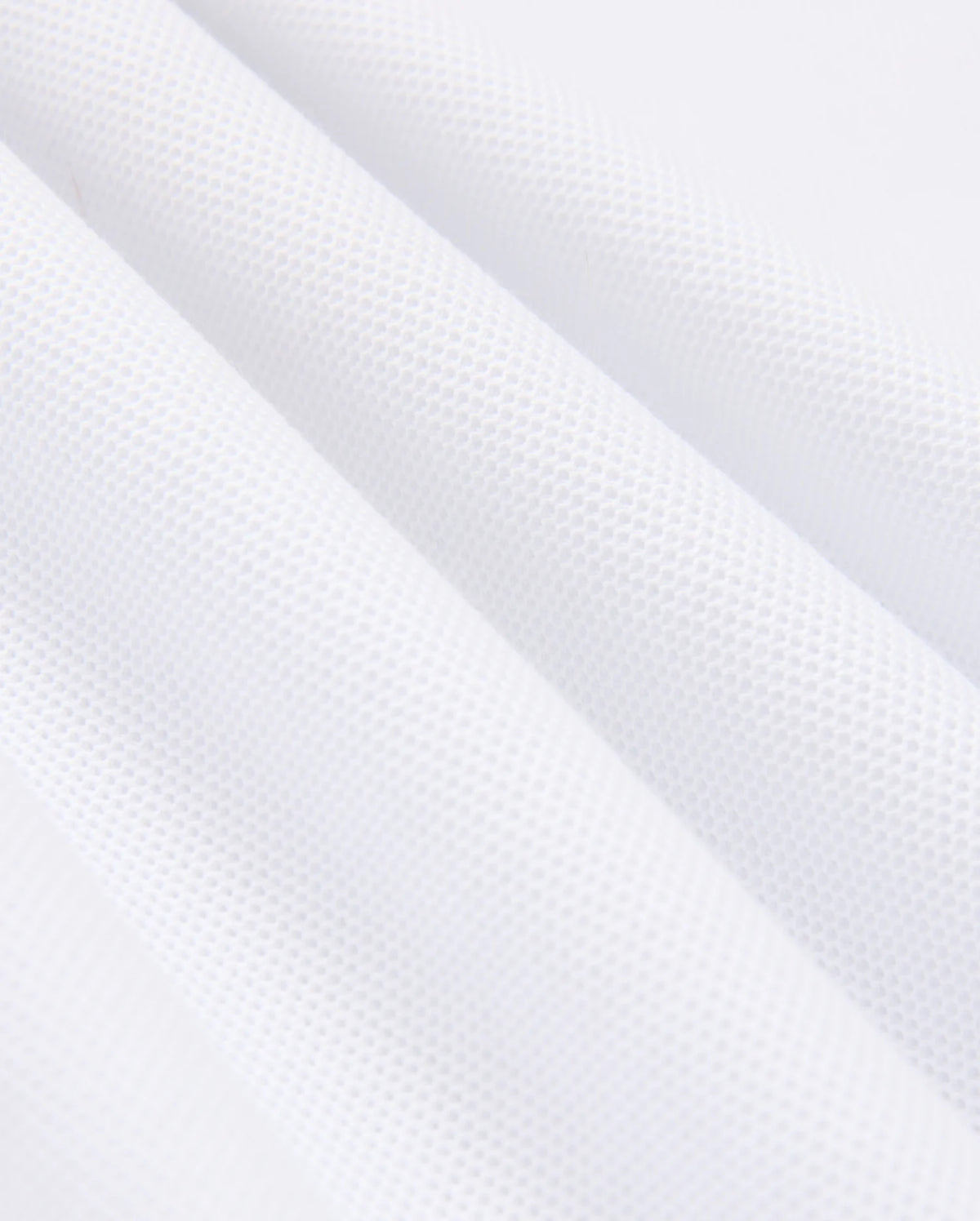 Close-up of a white, textured MENS KINGSTON PIQUE POLO SHIRT - B6K764D200 by Psycho Bunny, made from soft Pima cotton with a subtle waffle pattern. The fabric is shown in folds, highlighting its texture and softness. The image captures the intricacies of the material, emphasizing the small, raised squares that create the waffle effect.