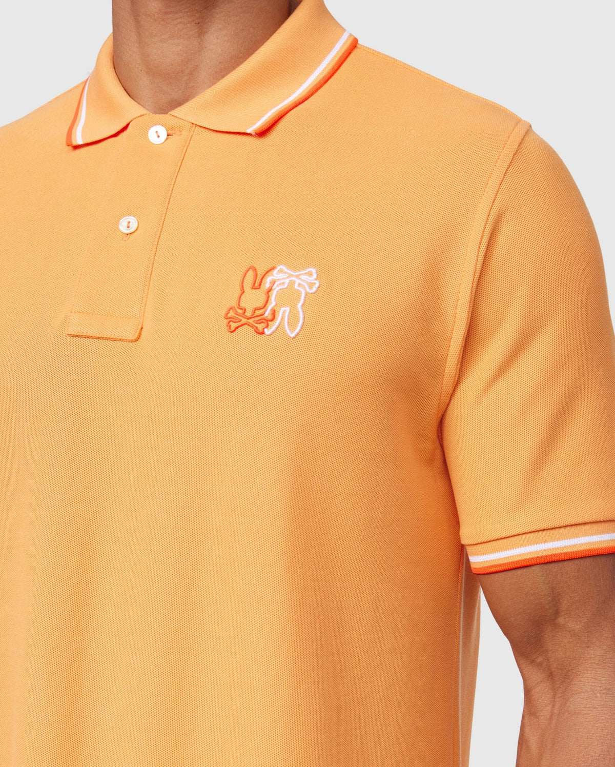 A man wearing a Psycho Bunny MENS WINTON PIQUE POLO SHIRT - B6K841A2PC in vibrant orange, crafted from luxurious Peruvian Pima cotton with a diamond-knit piqué texture.