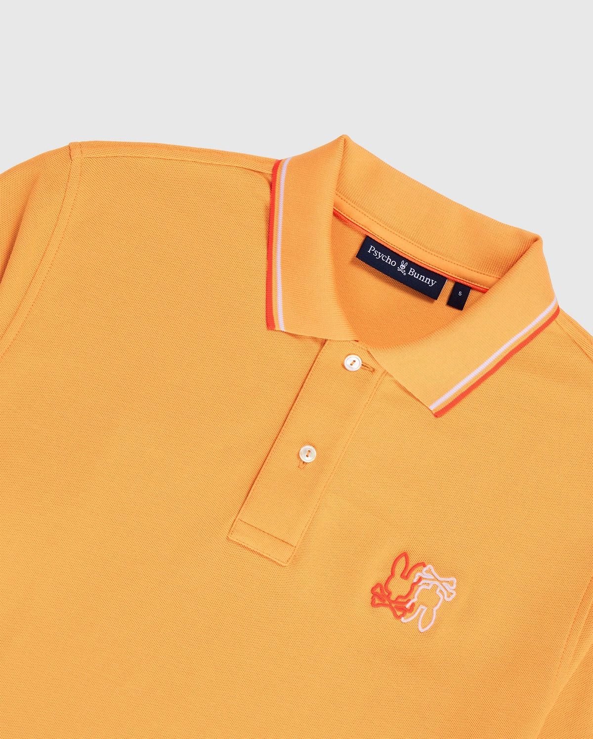 An orange men's Winton polo shirt made from Peruvian Pima cotton, featuring white and orange stripes on the collar. It has a white embroidered bunny logo on the left chest and a "Psycho Bunny" label inside. The shirt is laid flat against a white background, showcasing its premium diamond-knit piqué fabric. This product is the MENS WINTON PIQUE POLO SHIRT - B6K841A2PC by Psycho Bunny.