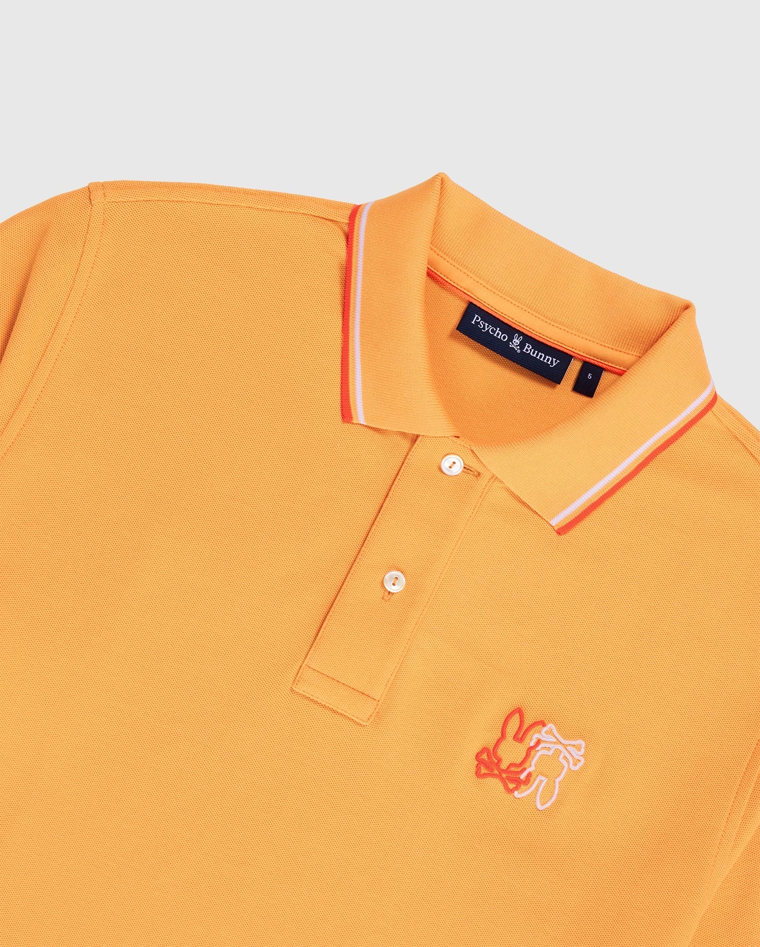 An orange men's Winton polo shirt made from Peruvian Pima cotton, featuring white and orange stripes on the collar. It has a white embroidered bunny logo on the left chest and a "Psycho Bunny" label inside. The shirt is laid flat against a white background, showcasing its premium diamond-knit piqué fabric. This product is the MENS WINTON PIQUE POLO SHIRT - B6K841A2PC by Psycho Bunny.