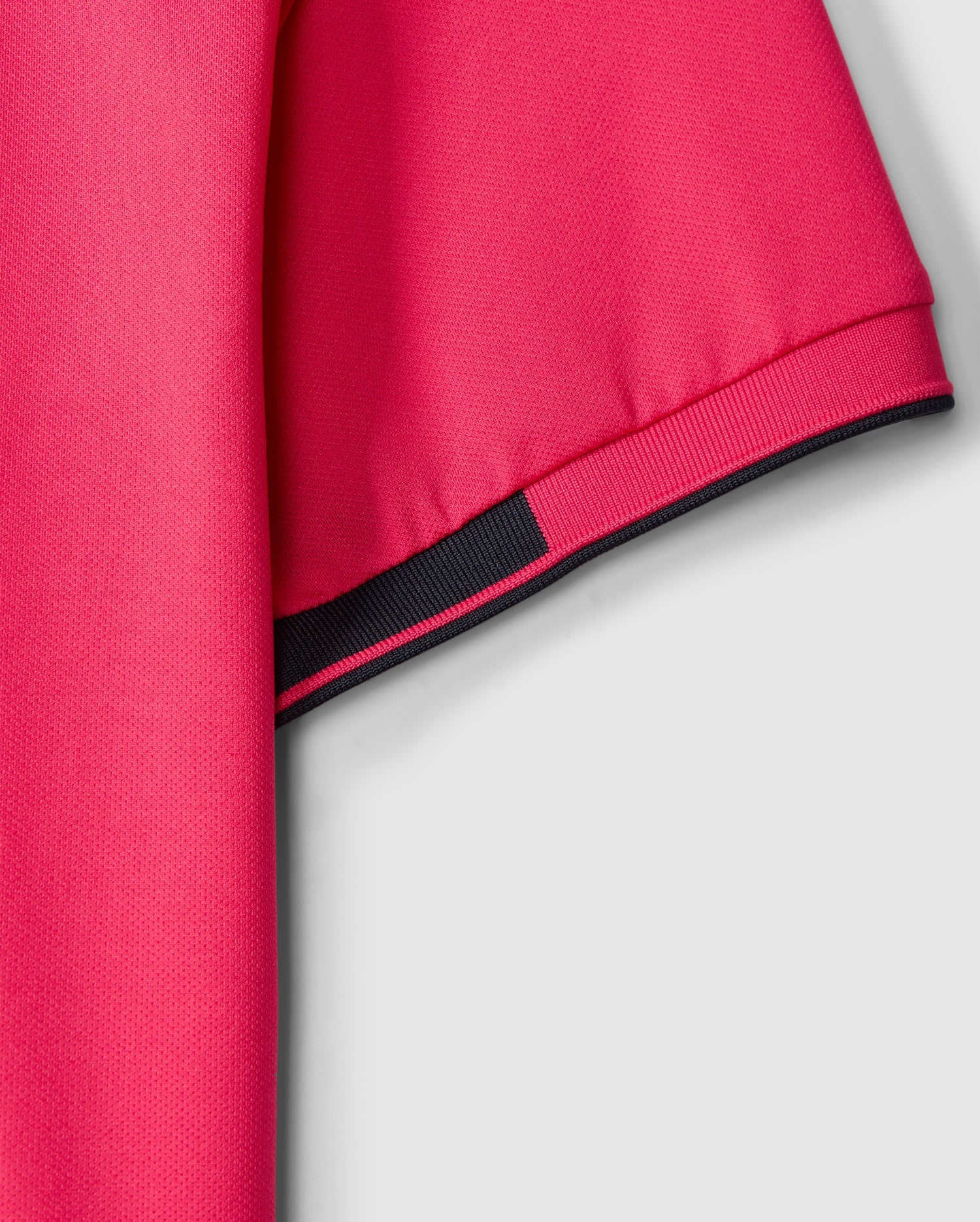 The Psycho Bunny MENS BELLEVUE SPORT POLO SHIRT - B6K905D200 is featured in a close-up shot against a gray background, illustrating its pink short sleeves accented with black trim. This men's athletic knit polo is made from textured fabric that highlights the weave of the material, offering both style and versatility for various activities.