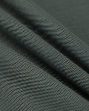 Close-up of the Psycho Bunny MENS KENT PIQUE POLO SHIRT in dark grey, featuring a textured weave pattern reminiscent of stylish polo fabric. The material is folded to form diagonal lines across the image, emphasizing its sturdy and dense quality.