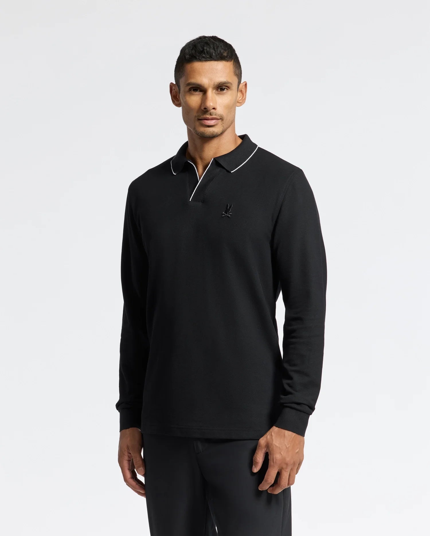 A person wearing the Psycho Bunny MENS CREEDE PIQUE JOHNNY COLLAR POLO - B6M265E200, made from soft Pima cotton with a white-trimmed Johnny collar, stands against a plain white background.