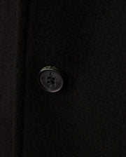 Zoom in on the refined black button of the Psycho Bunny Men's Stafford Wool Blend Coat - B6N551D200. This elegant winter coat boasts a four-hole button with discreet text around it and its wool blend fabric offers a soft, slightly textured look.