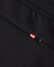 Close-up of a zippered black Psycho Bunny MENS TRAVIS TRACK PANT - B6P143D200 made from high-quality cotton-blend fabric with a bright pink zipper pull tab. The fabric appears smooth and uniformly dark, while the zipper pull stands out due to its contrasting vivid color.
