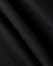 Close-up of the MENS TRAVIS TRACK PANT - B6P143D200 fabric by Psycho Bunny, showcasing a smooth and slightly shiny texture with subtle diagonal lines. Crafted from high-quality cotton-blend material, it appears gently folded, creating soft creases and a streamlined appearance.