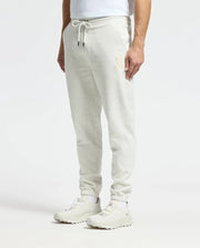A person wears Psycho Bunny's light gray Eldorado Brush Back Jogger (B6P285E200) with a drawstring and white sneakers. The pants have a subtle Chenille Bunny logo on one leg, harmonizing style and comfort against a plain backdrop.