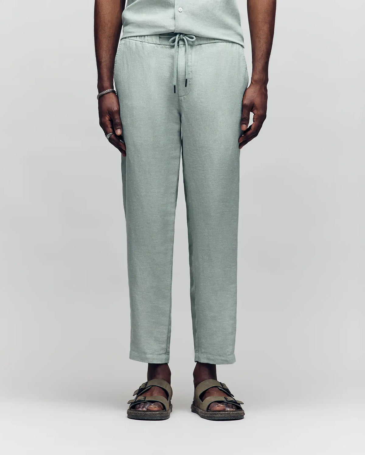 Psycho Bunny light green linen pants with a drawstring waist, relaxed fit, and subtle texture, showcasing refined streetwear style.