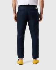 A man in a white shirt and Psycho Bunny MENS FATE LINEN DRAWSTRING PANT - B6P471C200, stands with his back facing the camera, hands down by his sides. He is wearing bright yellow shoes. The background is plain and light gray.