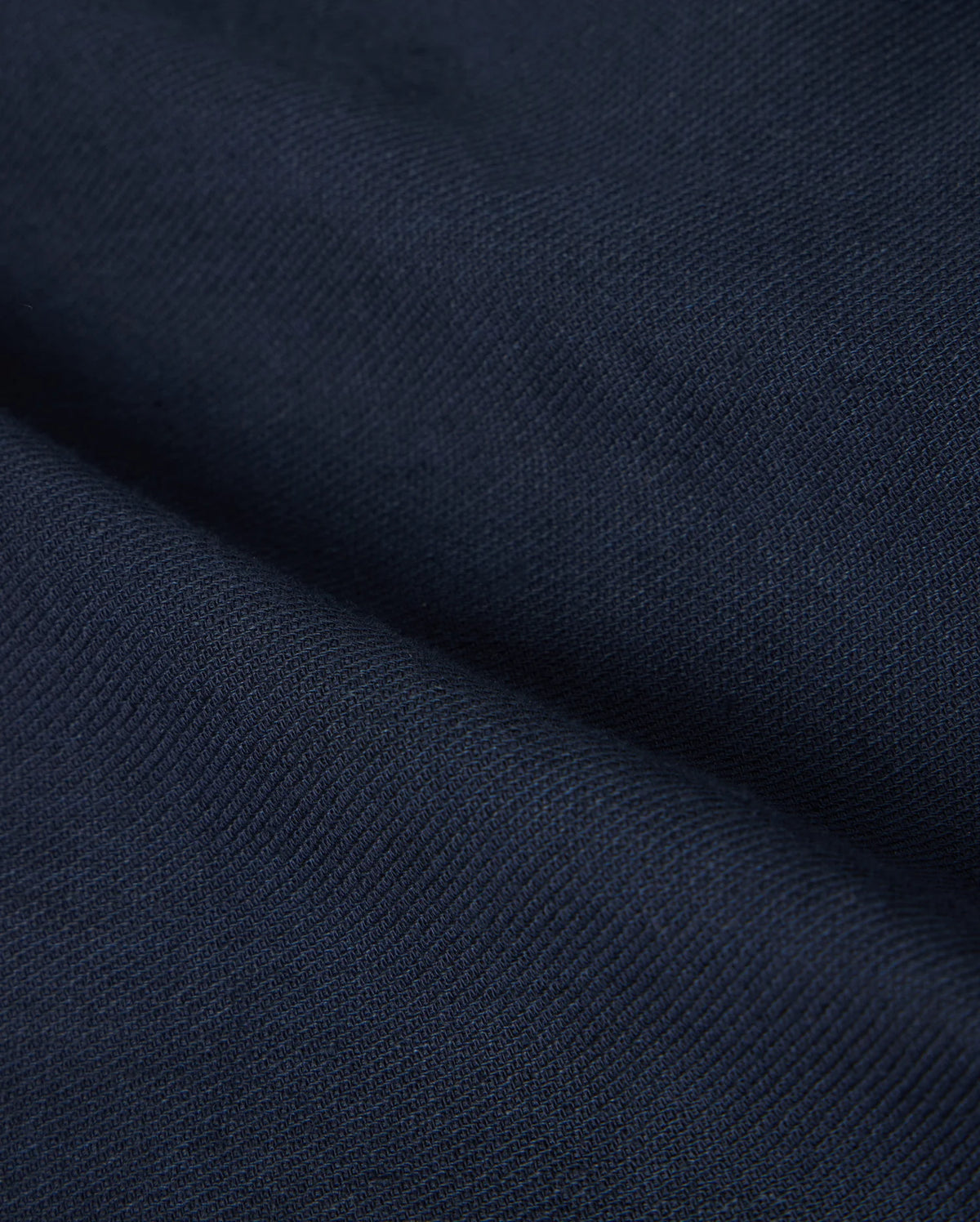 Close-up of the deep navy fabric with a textured surface, reminiscent of the Psycho Bunny MENS FATE LINEN DRAWSTRING PANT - B6P471C200. The material appears to be folded, creating visible creases and shadows that add depth to the image.