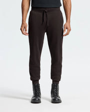 A person in Psycho Bunny's MENS LEVY ESSENTIAL FLEECE SWEATPANT (B6P721D200) and black lace-up boots stands against a white background, exuding a relaxed vibe with their arms at their sides.