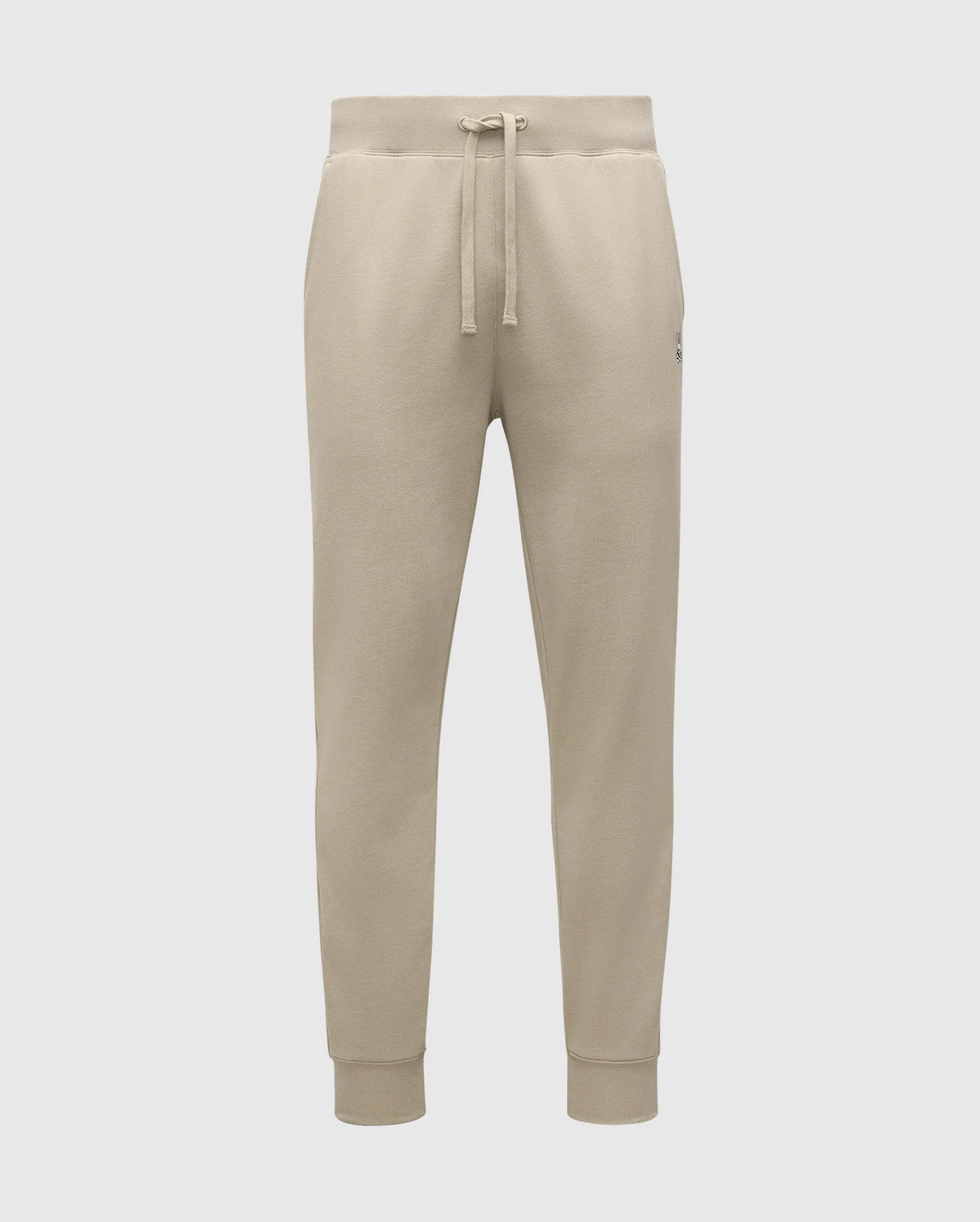 The MENS LEVY ESSENTIAL FLEECE SWEATPANT - B6P721D200 by Psycho Bunny are beige, ultra-soft joggers for men. They feature an elastic waistband with a drawstring, cuffs at the ankles, and a small logo on the left thigh. Made from cozy cotton fabric, these sweatpants are soft and comfortable, making them ideal for casual wear.