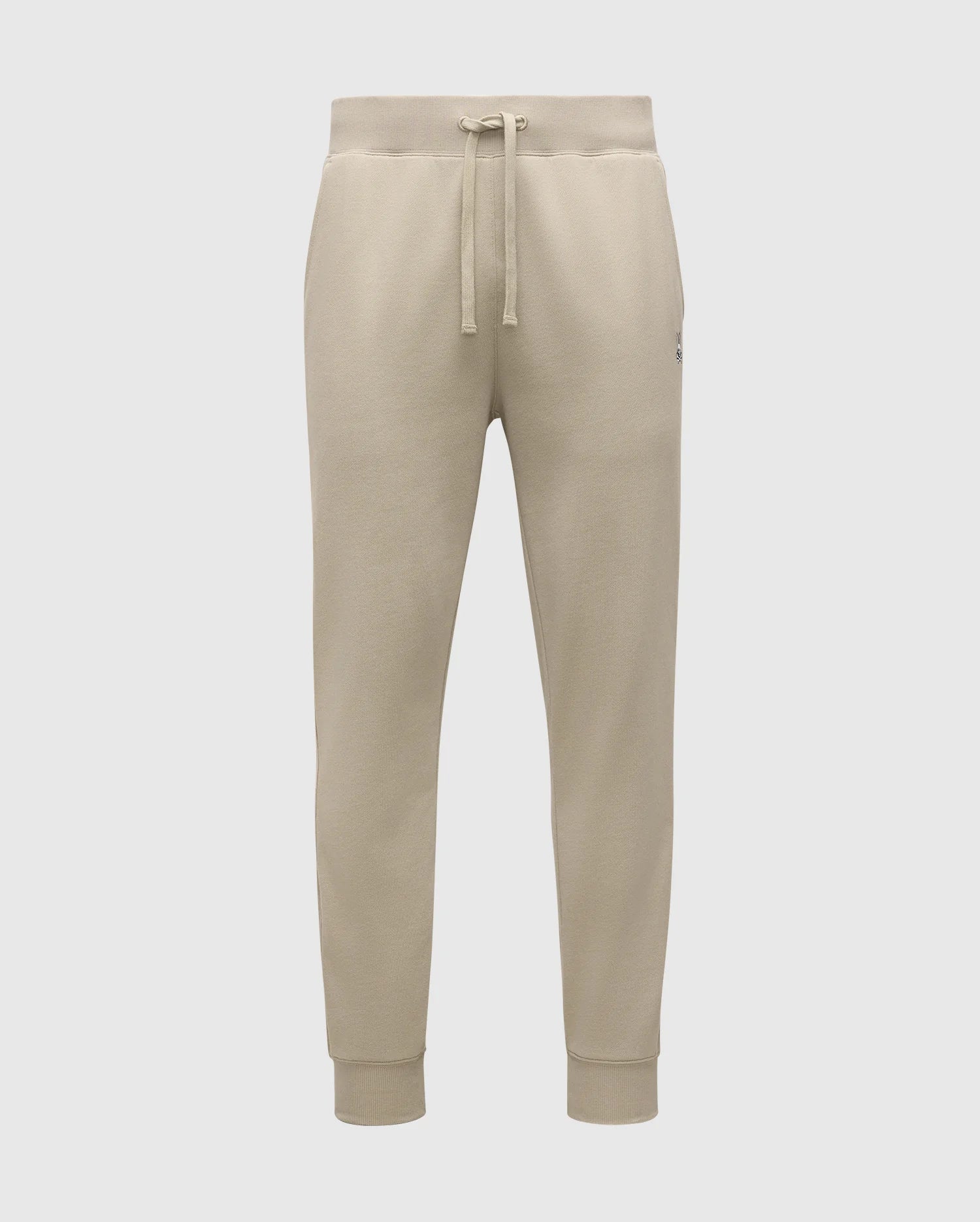 The MENS LEVY ESSENTIAL FLEECE SWEATPANT - B6P721D200 by Psycho Bunny are beige, ultra-soft joggers for men. They feature an elastic waistband with a drawstring, cuffs at the ankles, and a small logo on the left thigh. Made from cozy cotton fabric, these sweatpants are soft and comfortable, making them ideal for casual wear.
