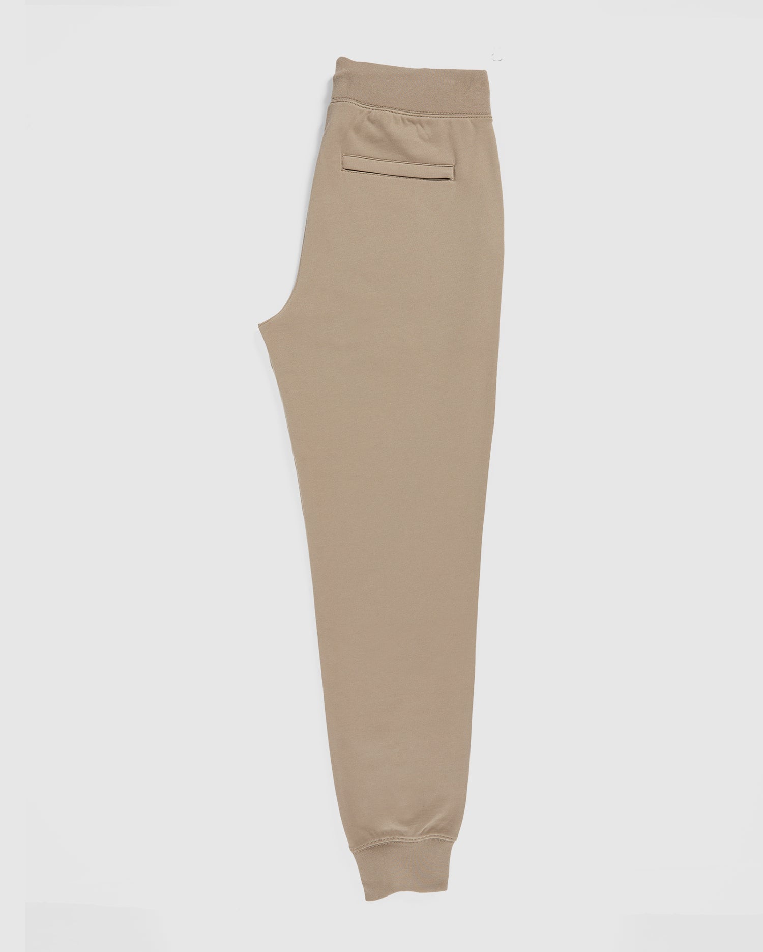 A pair of MENS FRENCH TERRY KNIT SWEATPANTS by Psycho Bunny, B6P828ARFT, in classic fit and beige color, laid flat on a white background. These joggers have an elastic waistband, a back pocket, ribbed ankle cuffs, and are made from soft French terry fabric for ultimate comfort.
