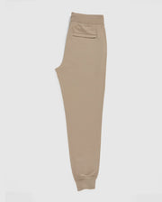 A pair of MENS FRENCH TERRY KNIT SWEATPANTS by Psycho Bunny, B6P828ARFT, in classic fit and beige color, laid flat on a white background. These joggers have an elastic waistband, a back pocket, ribbed ankle cuffs, and are made from soft French terry fabric for ultimate comfort.