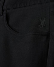 Close-up of a black denim pocket on the Psycho Bunny MENS HAYS TWILL PANT - B6P894D200, featuring an embroidered rabbit's head with crossed bones beneath it. This subtle design detail enhances this regular fit piece, crafted from a cotton-blend twill.