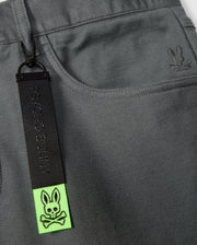 Introducing the Psycho Bunny MENS HAYS TWILL PANT - B6P894D200 in a gray cotton-blend twill. This regular fit design showcases an embroidered rabbit logo on the right side and comes with a striking black and neon green keychain adorned with a skull and crossbones rabbit motif attached to the pocket.